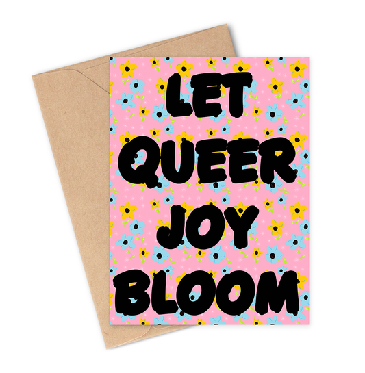 Greeting card with 'Let Queer Joy Bloom' text on a pink floral background with a brown envelope.