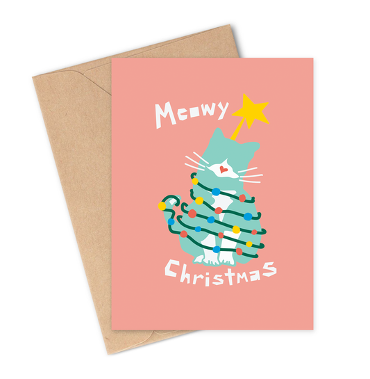 Greeting card with a Christmas tree wrapped in fairy lights and cat illustration on a pink background, accompanied by a brown envelope.